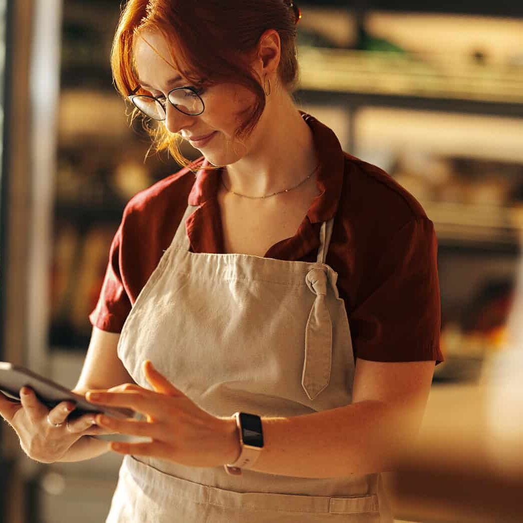 grocery store inventory management woman using a tablet in a bakery or cafe setting.
