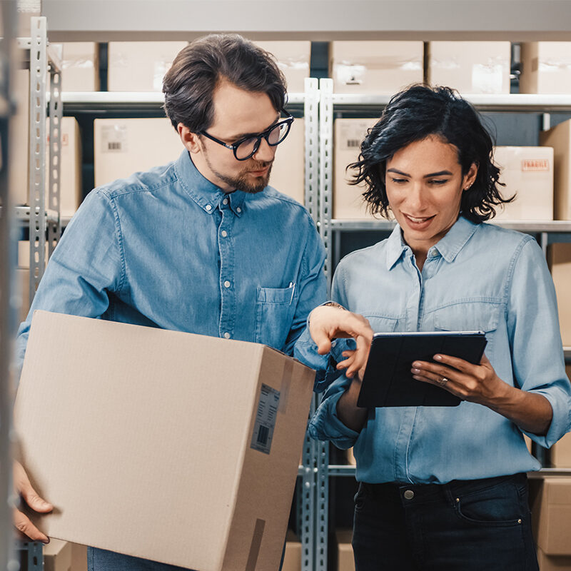 Inventory specialists inspecting stock in warehouse, reviewing inventory data on digital tablet, managing stock levels, supply chain management, logistic professionals working together for accurate inventory control.