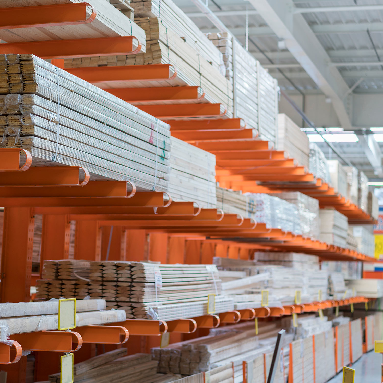 - Stacked lumber on industrial orange metal shelving in a warehouse.