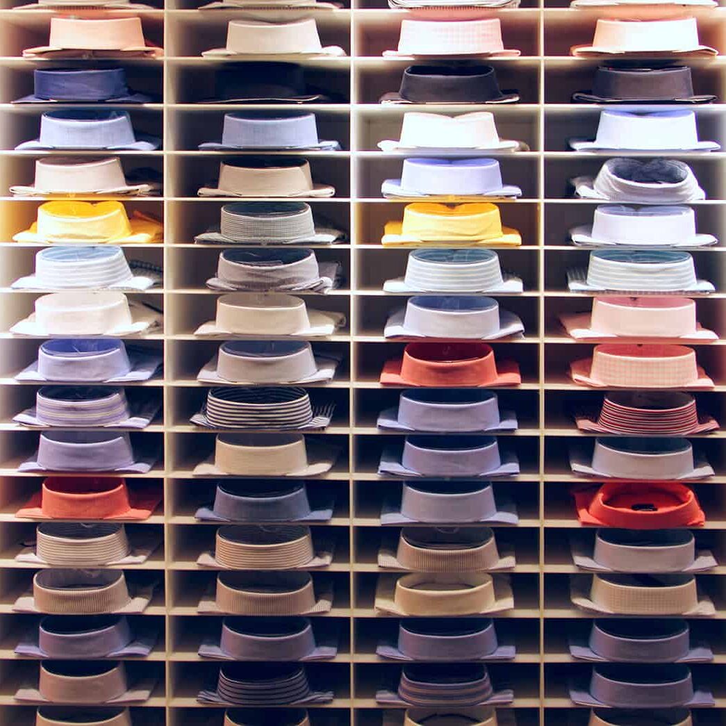 Neatly organized shelves filled with various colorful men's dress hats, showcasing inventory management and storage solutions for apparel in a retail or warehouse setting.